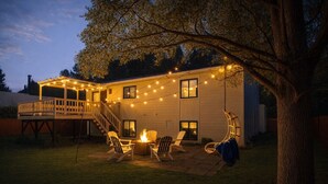 Ein Haus mit überdachter Terrasse, Sitzgelegenheiten im Freien und Lichterketten.