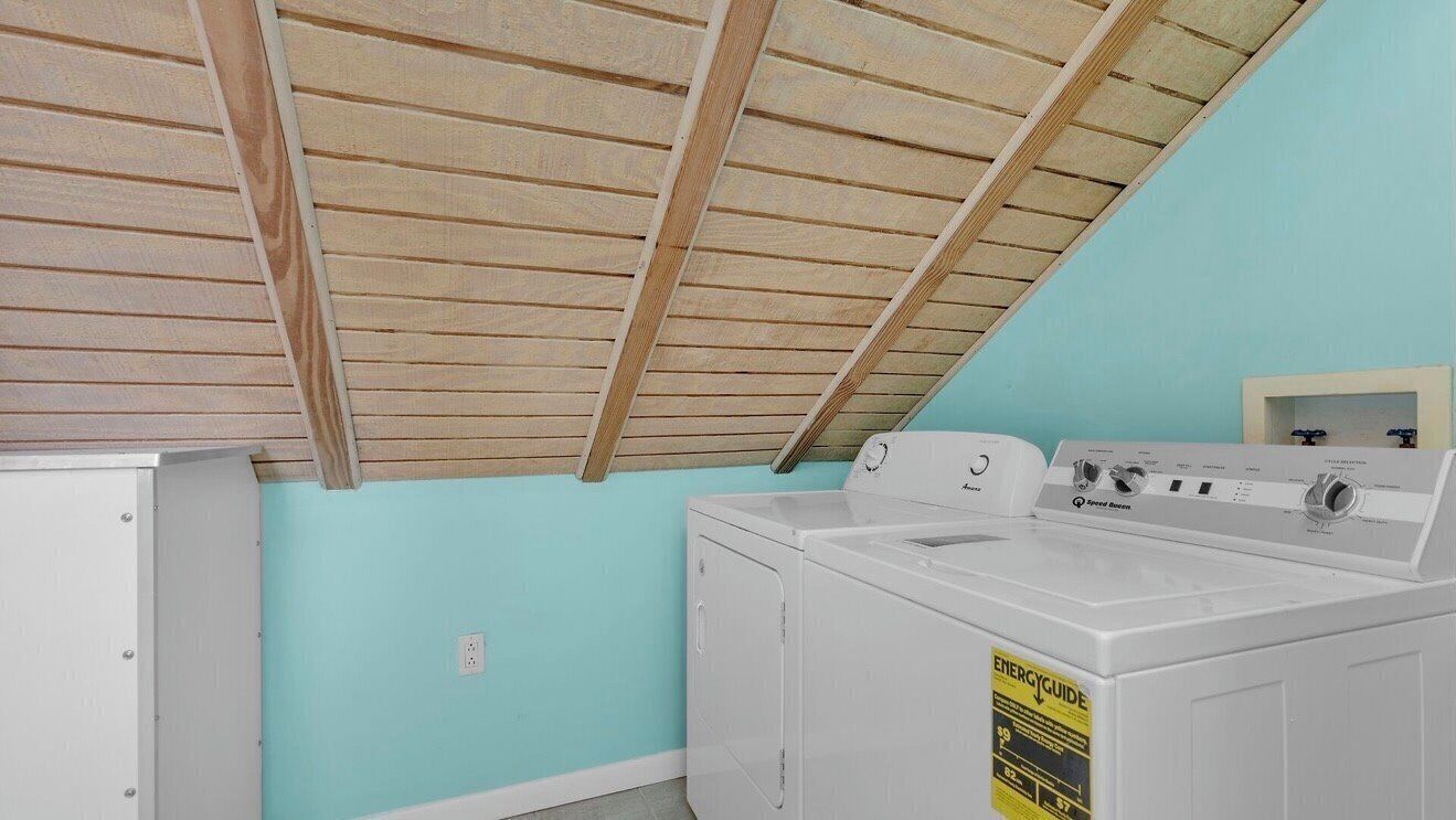 Una lavanderia con ventilatore a soffitto, lavatrice e asciugatrice.