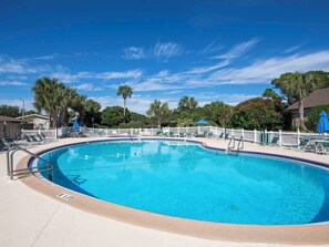 A clear blue swimming pool surrounded by a white fence, with lounge chairs and umbrellas. - Seascape Condo #407 (Miramar Beach)