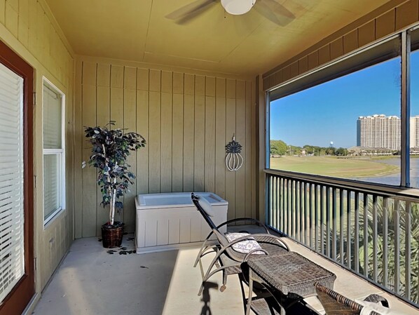 A covered porch with a view of a golf course and buildings. - Seascape Condo #407 (Miramar Beach)