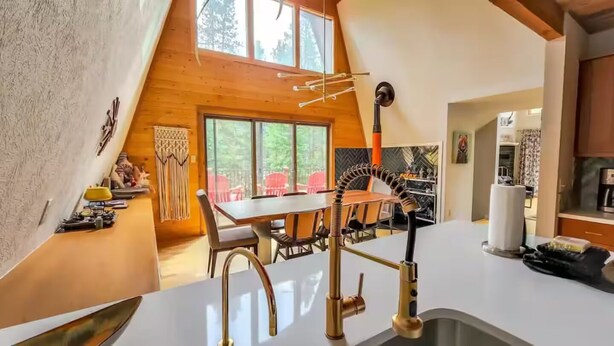 A modern kitchen with a white countertop, a gold faucet, and a dining area with a table and chairs. - Spacious Mid Century 3 bed 3 bath with Hot Tub! (Breckenridge)