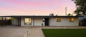 Ein eingeschossiges Haus mit Eingangstür, Garage und kleinem Vorgarten mit Rasen.