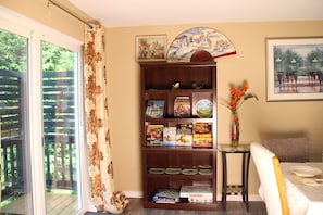 Un comedor con una mesa dispuesta para dos personas, una estantería con libros de cocina y vistas a través de un ventanal.