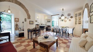 A dining area with a checkered floor, wooden furniture, and a central table with a lace tablecloth. - Villa Ariadne - Sea View Sanctuary (Idra)