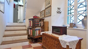 A staircase leading to a second floor, a wooden chest of drawers, a bookshelf, and a window with a view. - Villa Ariadne - Sea View Sanctuary (Idra)