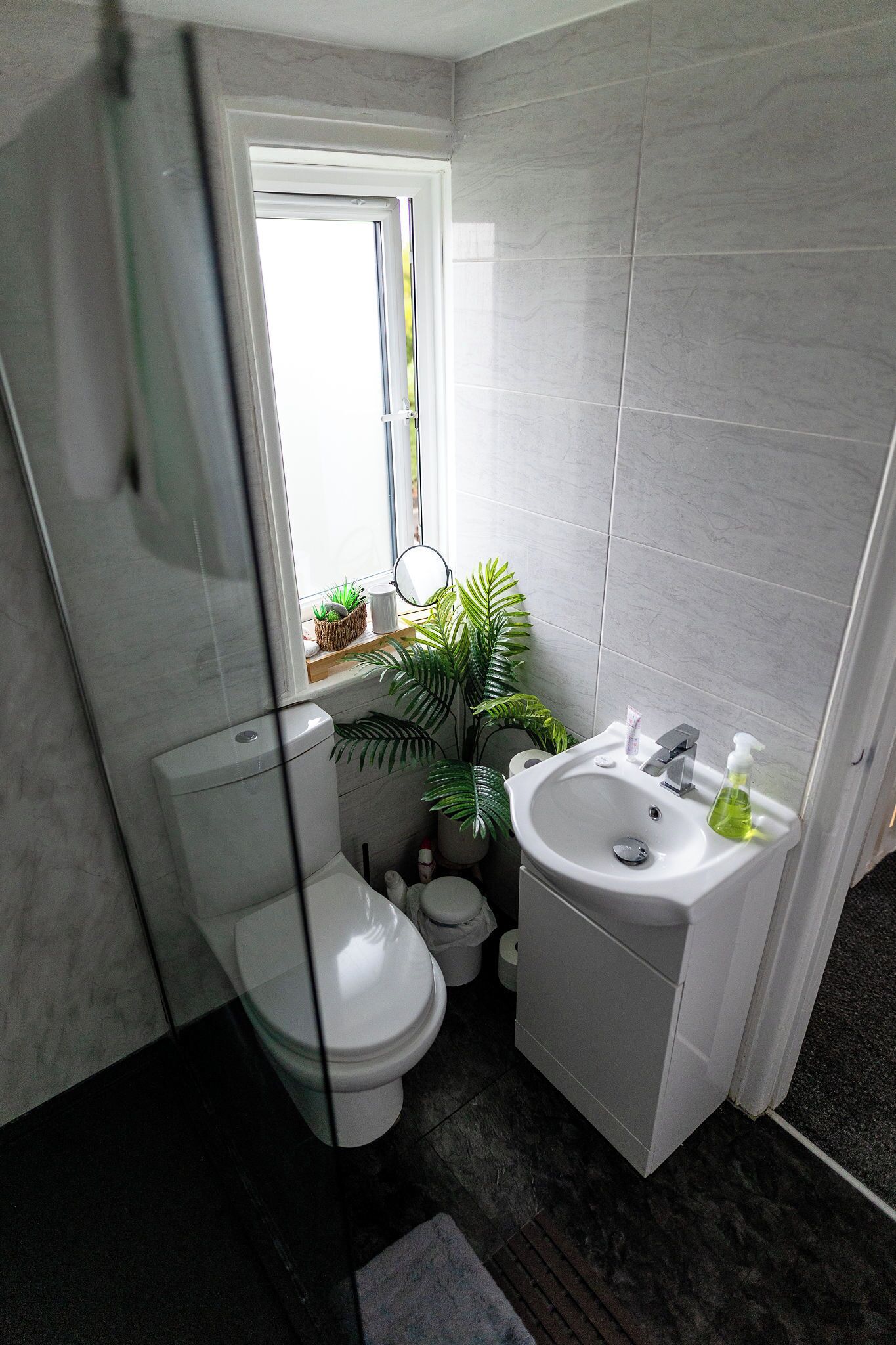 A compact bathroom with a toilet, sink, and window.