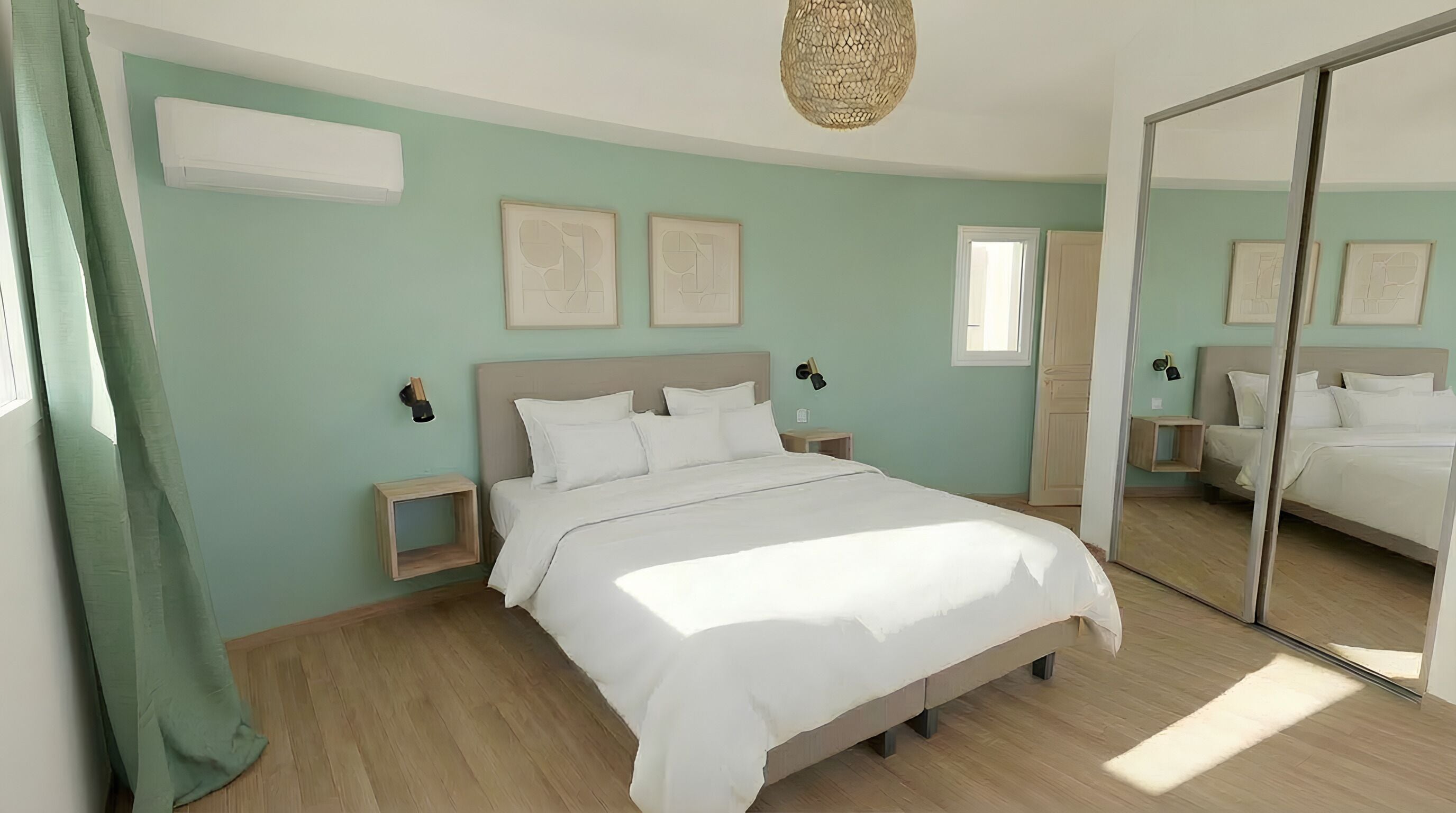 A bedroom with a bed, bedside tables, a mirror, and a window.
