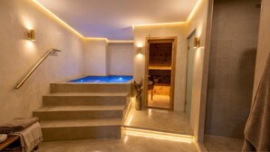 A modern bathroom with a built-in hot tub, a wooden bench, and a towel rack. - The Pearl of Paradise (Marigot)