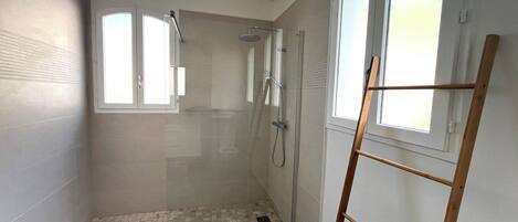 Baño con puerta de vidrio, escalera de madera y ventana.