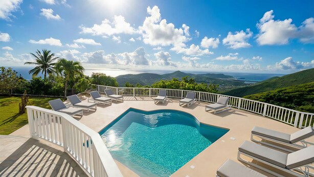 A poolside area with lounge chairs and a view of the ocean and hills. - The Pearl of Paradise (Marigot)