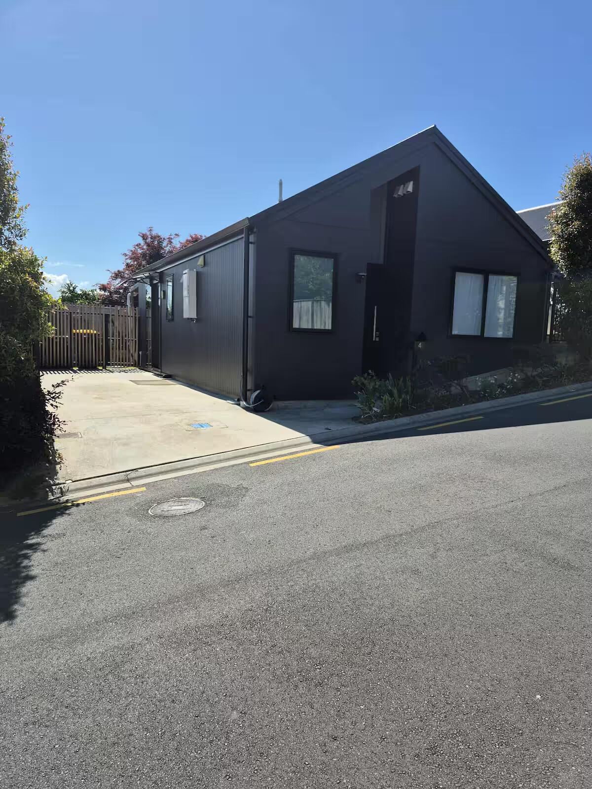 A modern building with a dark exterior, a gated entrance, and a paved driveway.