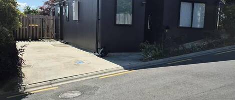 A modern building with a dark exterior, a gated entrance, and a paved driveway.