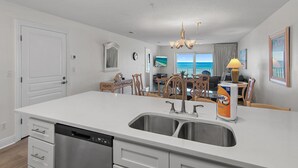 A modern kitchen with a large island, stainless steel sink, and a dishwasher. - Emerald Dunes 204*Pool*HotTub*Remodeled*Beach Gear (Destin)