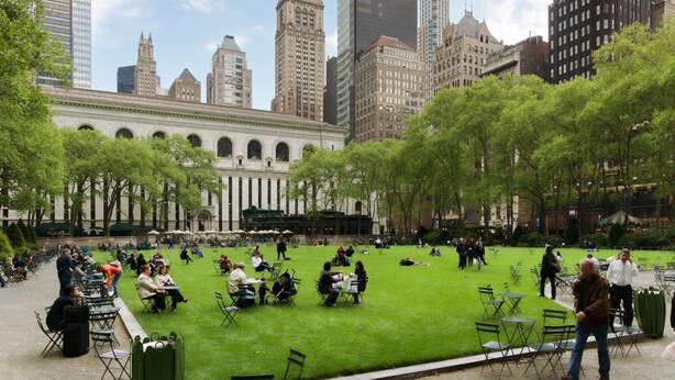 A park with tables and chairs, surrounded by tall buildings. - Steps to Madison Square Garden + Breakfast & Gym (New York)