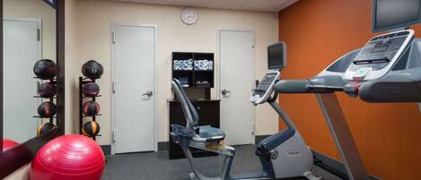 A gym with exercise equipment, a red exercise ball, and a treadmill.