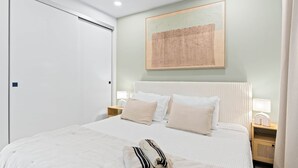 Ein Schlafzimmer mit einem Bett, Nachttischen, einem Wandbild und einer Tür.