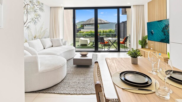 Ein modernes Wohnzimmer mit einer Couch, einem Esstisch und Blick ins Freie.