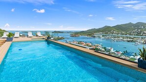 Ein Schwimmbecken mit Blick auf einen Yachthafen und Berge.