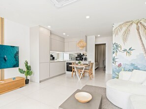 A modern living room with a sofa, a coffee table, and a TV mounted on the wall. - D402 - Beautiful apartment with garden and view (Cole Bay)