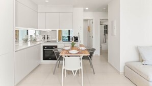 A modern kitchen with white cabinets, a dining table with chairs, and a view of the city through the window. - D432 Very beautiful apartment with a balcony (Cole Bay)