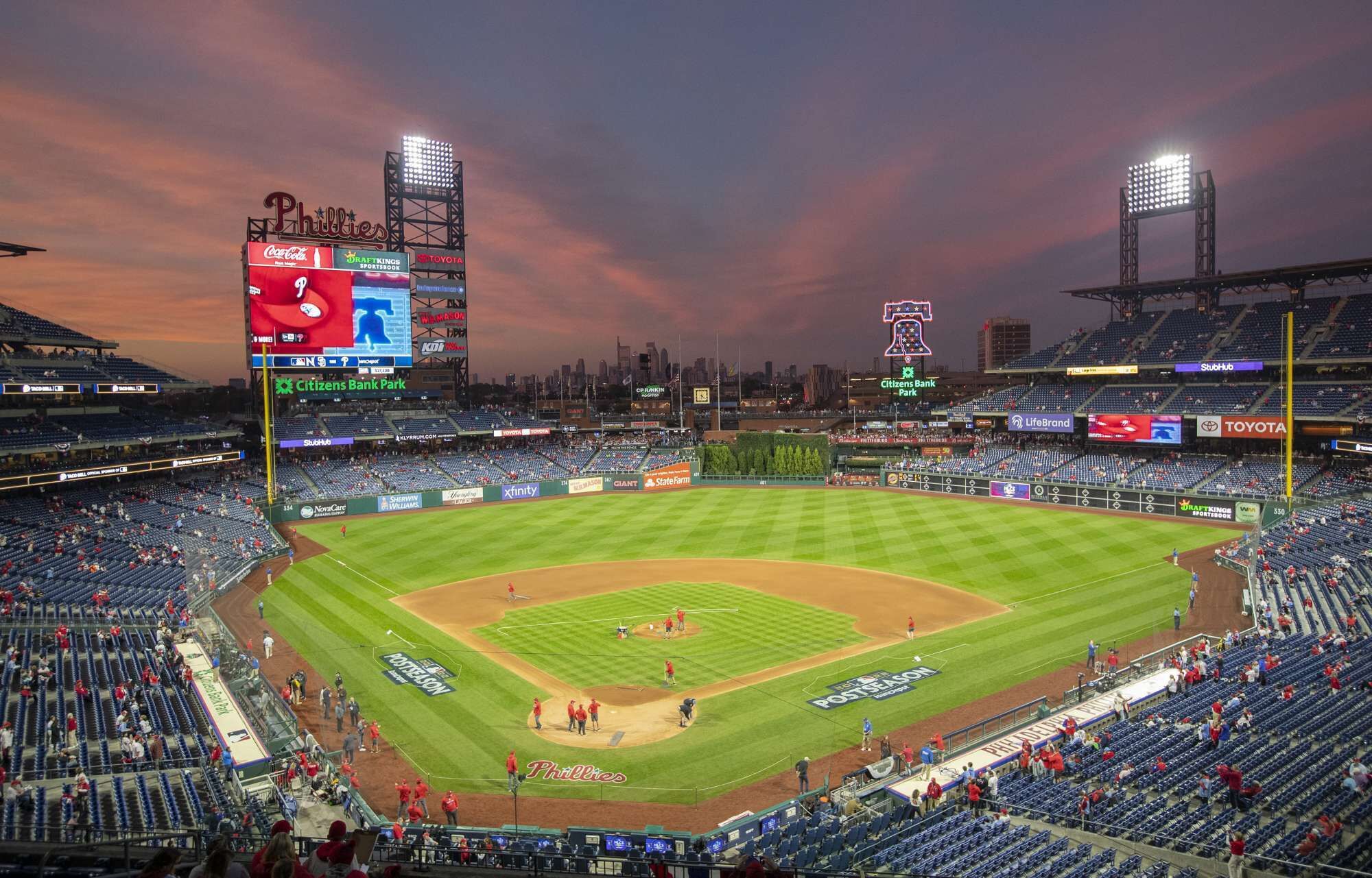 Un estadio de béisbol con varios niveles de butacas, un marcador grande y anuncios.