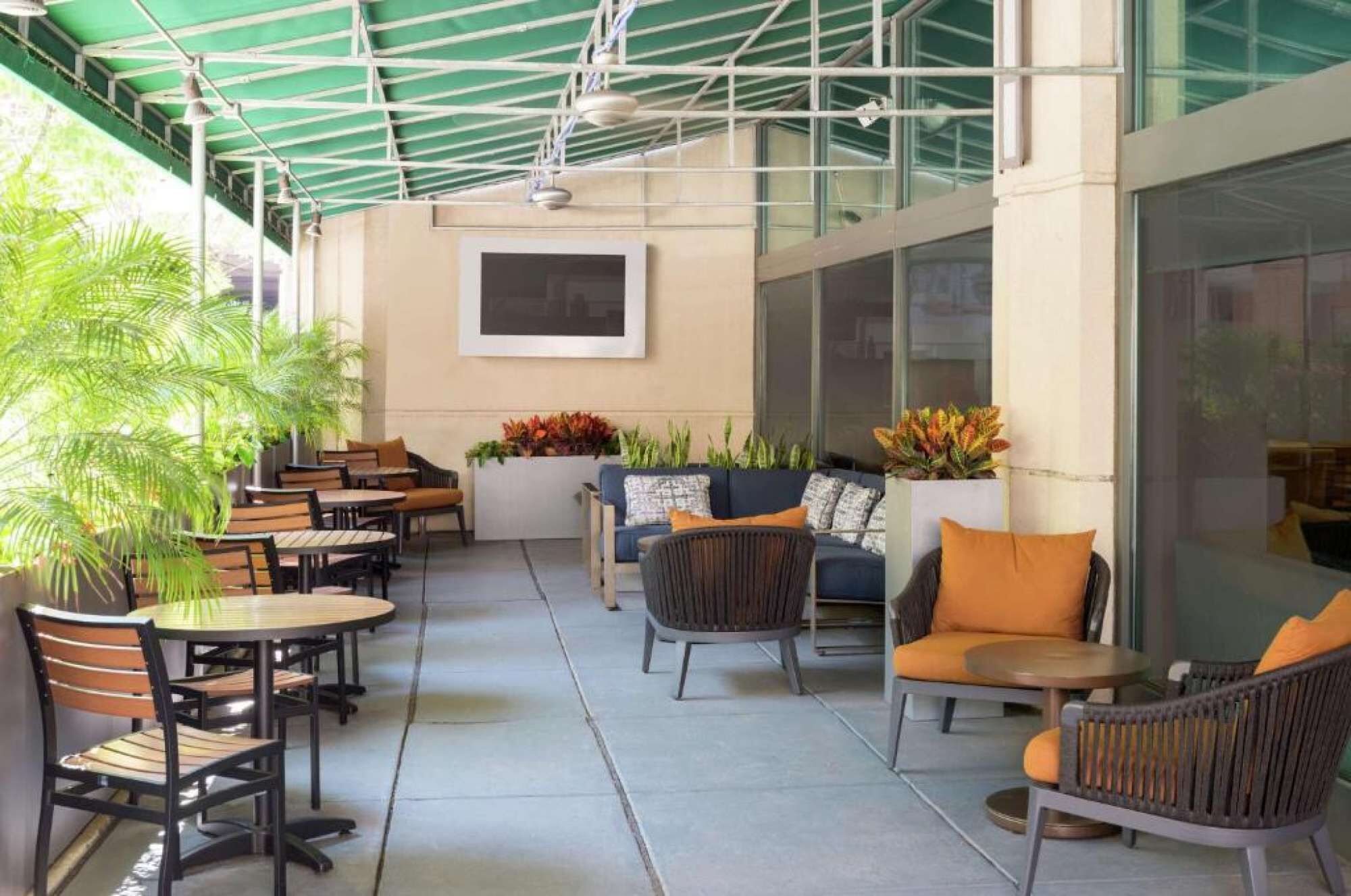 An outdoor patio area with tables and chairs, a sofa, and potted plants.