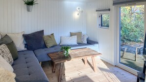 Een gezellige woonkamer met een hoekbank, een houten salontafel en een potplant.