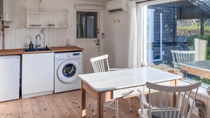 Een kleine keuken met een wasmachine, een houten tafel en stoelen.