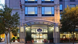A hotel entrance with a covered entryway, large windows, and a sign indicating it is the Hampton Inn. - Near Independence Hall + Free Breakfast. Bar. Gym. (Philadelphia)