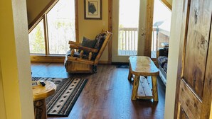 A wooden-floored interior with a wooden bench, a cushioned chair, and a small table. - Peaceful Rustic Mountain Getaway-Aspen Peaks Retreat (Hartsel)