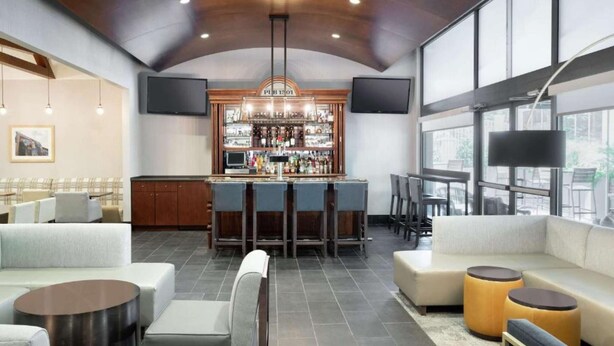 A modern bar area with a high ceiling, bar stools, and a well-stocked liquor shelf. - Near The Franklin Institute + Free Breakfast & Bar (Philadelphia)