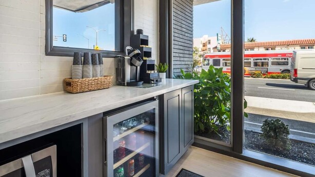 Een moderne keuken met een groot raam, een koffieapparaat en een koelkast.