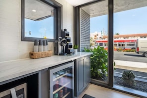 A modern kitchen with a large window, a coffee machine, and a refrigerator.