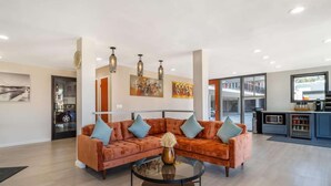 Een moderne woonkamer met een modulaire bank, een glazen salontafel en hanglampen.