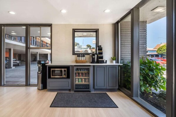 A modern kitchen with a built-in microwave, coffee machine, and beverage dispenser.