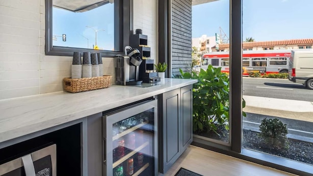 Een moderne keuken met een groot raam, een koffieapparaat en een koelkast.