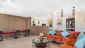 Een moderne hotellobby met een receptiebalie, een zithoek en een bank.