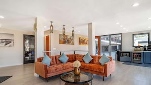 Een moderne woonkamer met een modulaire bank, een glazen salontafel en hanglampen.