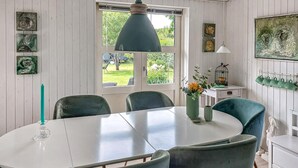 Ein Essbereich mit einem runden Tisch, Stühlen, einer Hängelampe und Bildern an den Wänden.