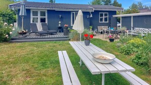 Ein blaues Haus mit einer Terrasse, Sitzgelegenheiten im Freien und einem Picknicktisch.