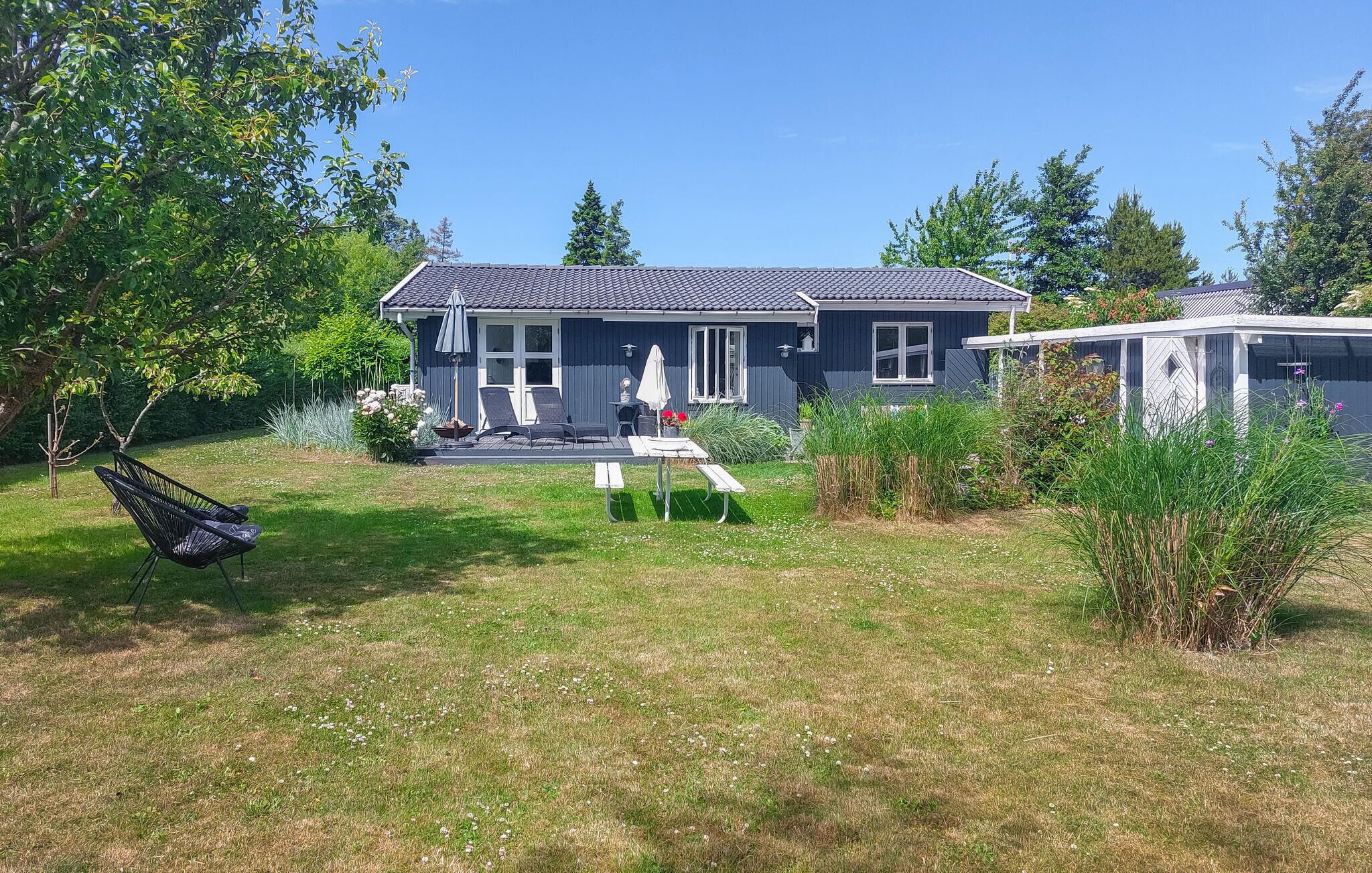 A house with a deck, a swing, and a garden.