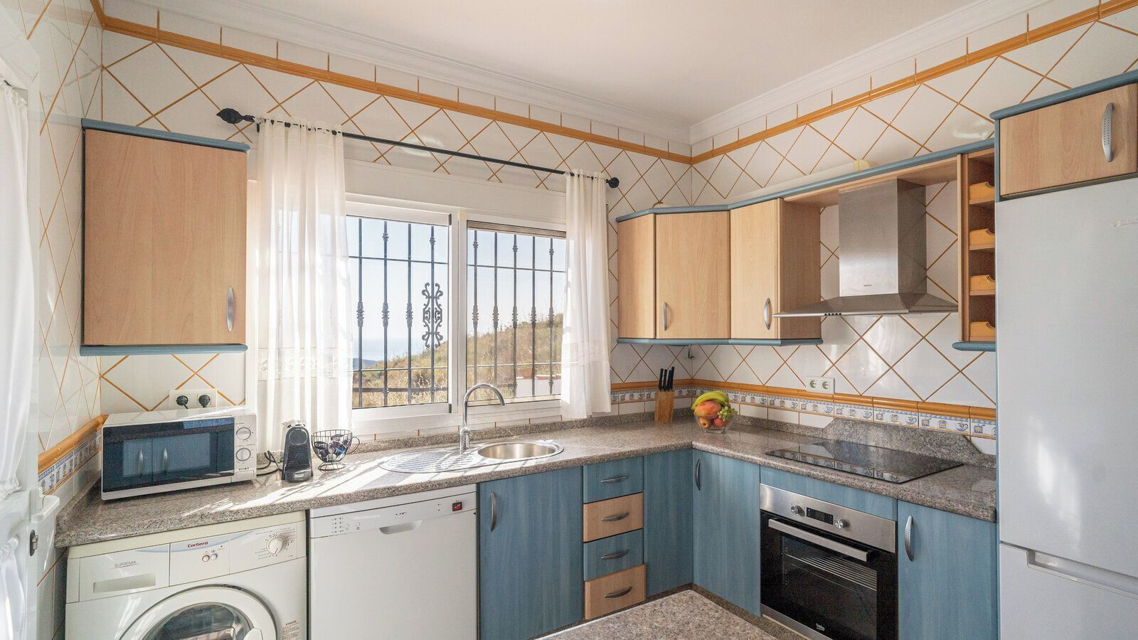 A compact kitchen with a washing machine, a microwave, a sink, and a stove.