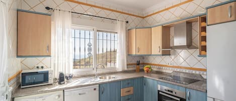 A compact kitchen with a washing machine, a microwave, a sink, and a stove.