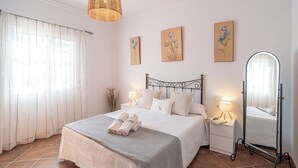 Een slaapkamer met een bed, nachtkastjes, een spiegel en kunst aan de muur.