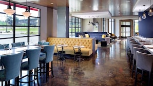 A spacious restaurant with a long counter, multiple seating areas, and large windows offering views of the outdoors. - Near The University of Alabama + Restaurant & Bar (Tuscaloosa)