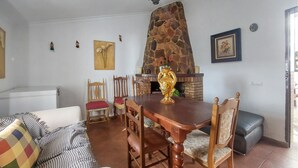 Un coin repas agrémenté d’une cheminée en pierre, d’une table à manger en bois et de chaises.