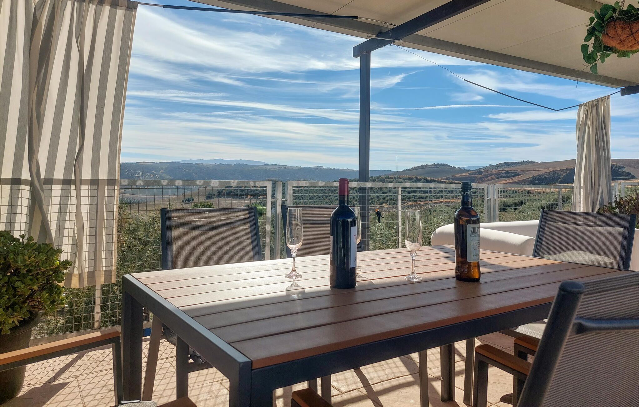 A terrace with a table, chairs, and a view of the countryside.