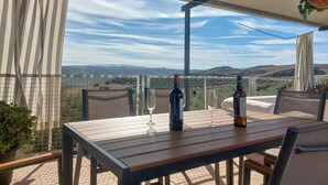 Une terrasse avec une table, des chaises et une vue sur la campagne.