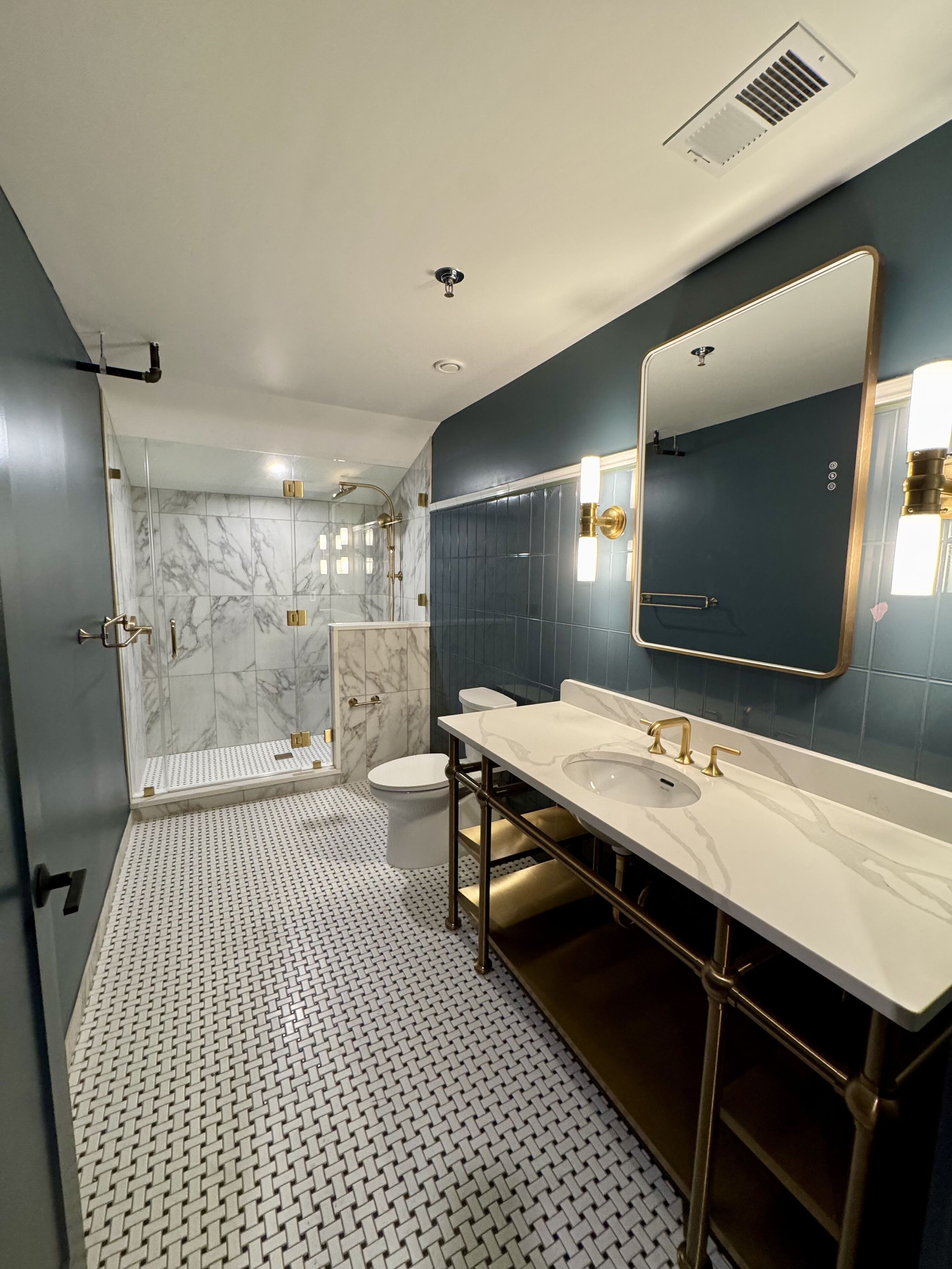 Un baño moderno con un espejo grande, dos lavamanos, una ducha y un inodoro.