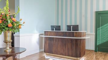A reception desk with a wooden finish, a vase with flowers, and a striped wall in the background.